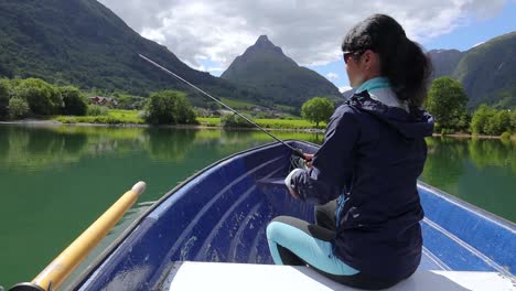Woman-on-the-boat-catches-a-fish-on-spinning-in-Norway.