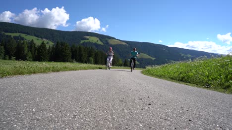 Couple-woman-and-man-on-electric-eco-bike-cycling-Italy-Dolomites-Alps