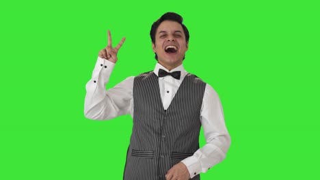 Happy-Indian-waiter-showing-victory-sign-Green-screen