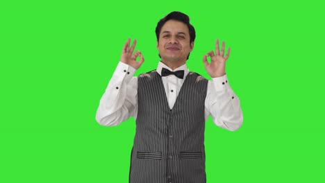Happy-Indian-waiter-showing-okay-sign-Green-screen