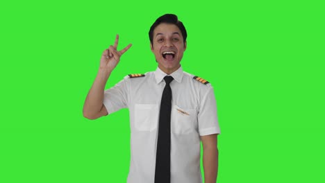 Fröhlicher-Indischer-Pilot-Zeigt-Siegeszeichen-Auf-Grünem-Bildschirm