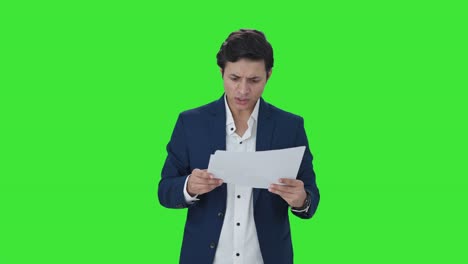 Stressed-Indian-manager-checking-reports-Green-screen