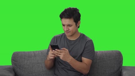 Frustrated-Indian-man-typing-on-phone-Green-screen