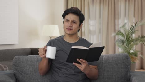 Verwirrter-Indischer-Mann,-Der-Ein-Buch-Liest-Und-Kaffee-Trinkt