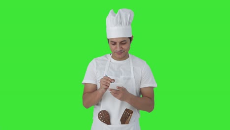 Happy-Indian-professional-chef-noting-down-recipe-Green-screen