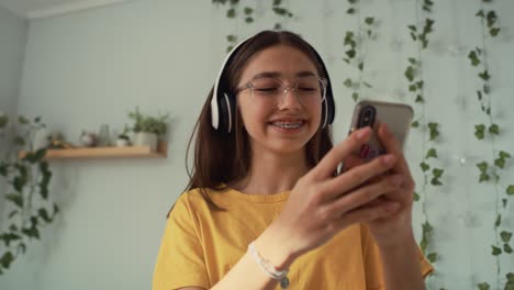Caucasian-teenage-girl-dancing-in-her-room-with-headphones-and-phone