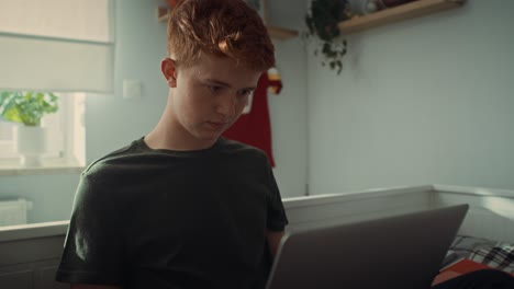 Niño-Adolescente-Caucásico-Sentado-En-La-Cama-Y-Escribiendo-En-La-Computadora-Portátil.