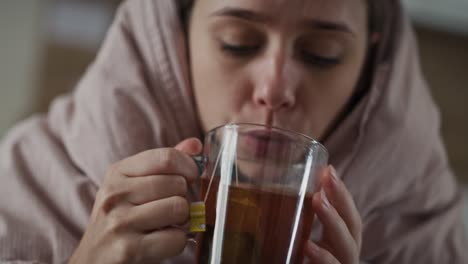 Caucasian-woman-sitting-under-the-duvet-with-tea-at-home.