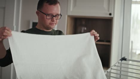Caucasian-adult-caucasian-man-with-down-syndrome-folding-laundry-by-himself