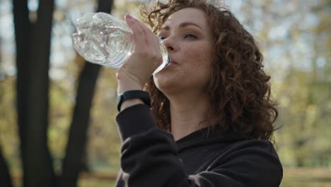 Mujer-Jengibre-Bebiendo-Agua-Durante-El-Freno-De-Correr-En-El-Parque