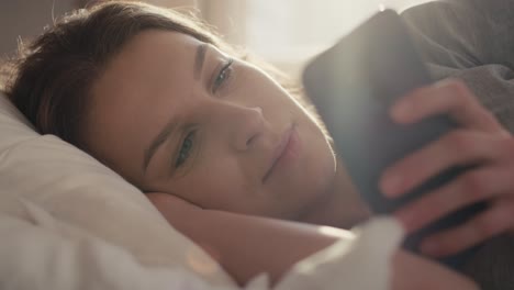 Caucasian-woman-lying-in-bed-at-morning-and-using-mobile-phone.