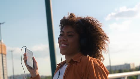 Black-woman-wearing-headphones-and-dancing-on-the-bridge.
