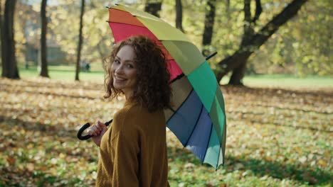 Kaukasische-Frau-Mit-Buntem-Regenschirm,-Die-Im-Herbstpark-Spaziert.