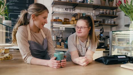 Down-syndrome-girl-and-her-female-workmate-chatting-during-a-short-break-at-work