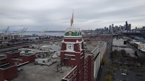 Clockwise-aerial-orbit-of-Starbucks-Coffee-Headquarters-Elliot-Bay-and-Seattle-skyline,-dull-gray-skies