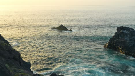 Panoramic-view-of-Los-Gigantes-sea-cliffs-at-sunset,-ocean-waves-spread-in-slow-motion