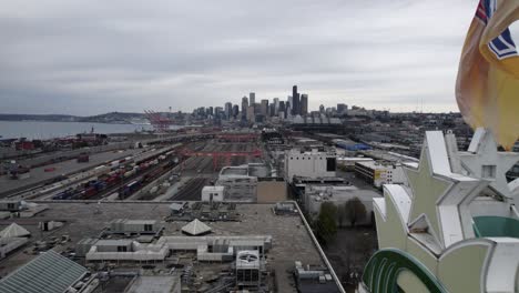 Flying-past-Starbucks-Coffee-Headquarters-Elliot-Bay-revealing-Seattle-skyline,-dull-gray-skies