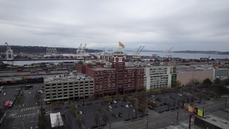 Wide-Angle-Aerial-orbit-of-Starbucks-Coffee-Headquarters-Elliot-Bay-and-Seattle-skyline,-dull-gray-skies