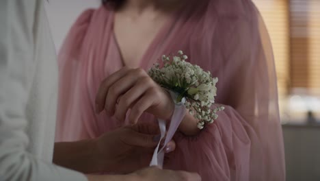 Unrecognizable--woman-applying-flower-corsage-on-girl's-wrist-before-prom