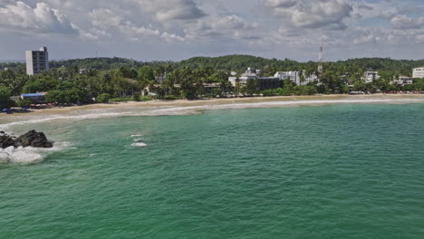 Mirissa-Sri-Lanka-Aerial-v10-drone-flyover-bay-capturing-beautiful-sandy-beach,-crystal-clear-water,-beachfront-resort-hotels-and-Udupila-coastal-town-views---Shot-with-Mavic-3-Cine---April-2023
