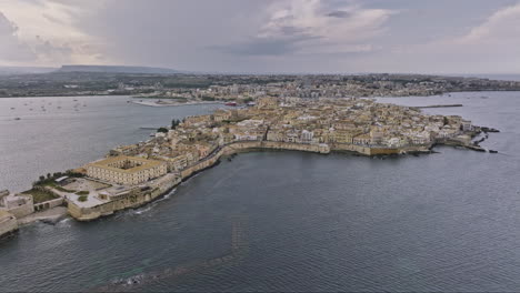 Syracuse-Italy-Aerial-v2-establishing-drone-flyover-capturing-ancient-old-city-of-Ortigia-Island-with-historical-stone-buildings-and-island-bounded-by-Ionian-sea---Shot-with-Mavic-3-Cine---June-2023