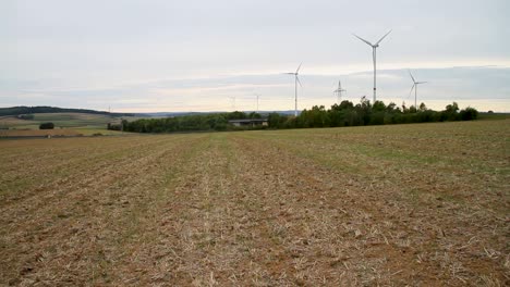 High-speed-electric-passenger-train-passing-through-green-valley-with-windmills