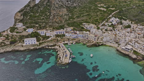 Levanzo-Italy-Aerial-v2-flyover-the-harbor-capturing-coastal-island-village-town-in-west-of-Sicily-with-rugged-cliffs,-crystal-clear-waters-of-the-Mediterranean-Sea---Shot-with-Mavic-3-Cine---May-2023