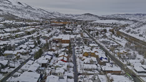 Park-City-Utah-Aerial-v77-flyover-along-main-street-across-town-center-capturing-buildings-and-houses-covered-in-pristine-snow,-and-winter-mountain-landscape---Shot-with-Mavic-3-Cine---February-2023