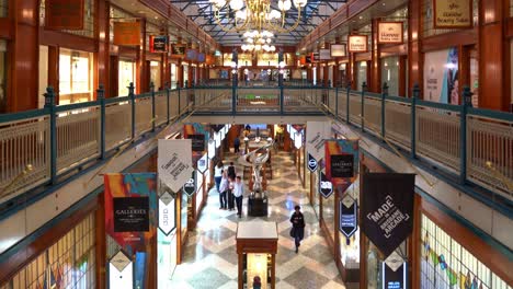 View-from-second-floor-capturing-the-interior-of-Brisbane-arcade-with-Mirage-sculpture-by-Gidon-Graetz-as-the-centrepiece,-shoppers-shopping-at-designer-boutiques-at-fashion-laneway,-Queen-street-mall