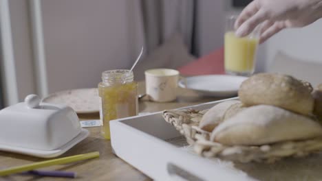 Man's-hands-serving-nutritious-breakfast-with-bread,-jam-and-orange-juice-with-tray