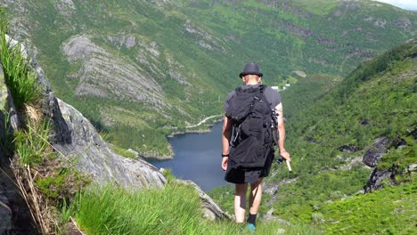 Man-complete-mountain-fishing-trip-and-proceeds-downhill-towards-Bergsdalen-Norway-while-holding-fishing-rod-in-hs-hand