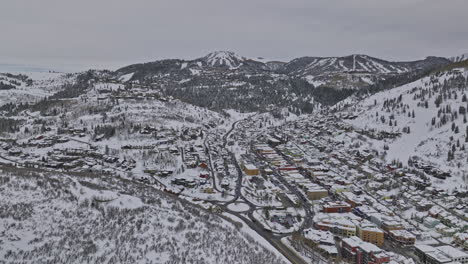Park-City-Utah-Aerial-v72-drone-flyover-and-around-downtown-capturing-hillside-homes,-ski-slopes-and-Wasatch-mountains-covered-in-pristine-white-snow-in-winter---Shot-with-Mavic-3-Cine---February-2023