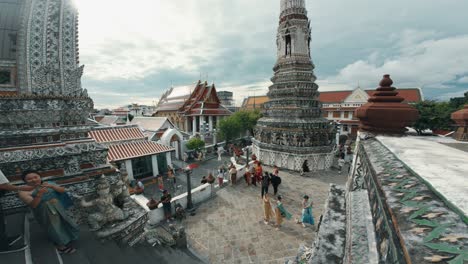 Tourists-exploring-the-renowned-Wat-Arun-Ratchawararam-Temple,-situated-on-the-banks-of-the-Chao-Phraya-River-in-Bangkok,-Thailand