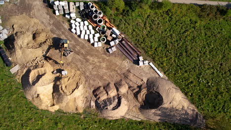 Birdseye-View-of-Earthmoving-Machine-on-a-Minesite,-Dirt,-Pipes,-Equipment
