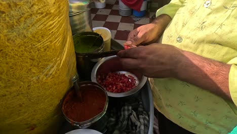 At-an-amusement-park,-a-shopkeeper-is-making-pads-and-fixing-tomatoes-and-chillies
