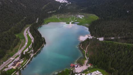 Aerial-shot-of-cars-driving-on-road-near-Lake-Dobbiaco,-Toblacher-See