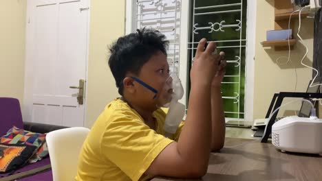 Asiatischer-Junge-Benutzt-Inhalator-Vernebler,-Während-Er-Mit-Seinem-Smartphone-Spielt