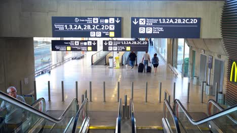 Information-signs-about-departure-terminals-at-Paris-Airport,-People-walking-and-moving-through-the-stairs,-France