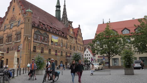 Pedestrians,-cyclists-in-courtyard-in-front-of-Ulm-Germany-Town-Hall,-or-rathaus