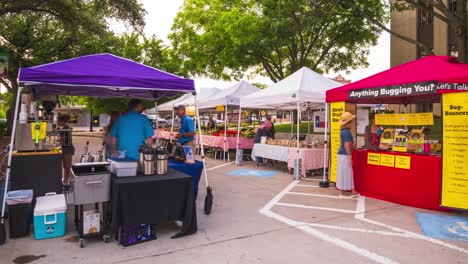 Vendors-and-locals-roam-through-farmers-market,-pop-up-tents-set-up-in-parking-lot