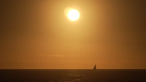 Yacht-sailing-on-the-oceans-horizon-during-a-golden-sunset