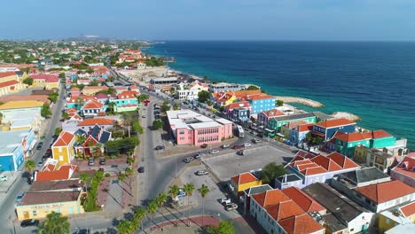 Aerial-establishing-view-of-Punda-district-as-tour-buses-and-cars-drive-streets-below,-Willemstad-Curacao
