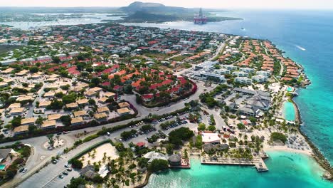 Beautiful-coastal-neighborhood-of-Jan-Thiel,-drone-tilts-down-over-Zanzibar-beach-Curacao
