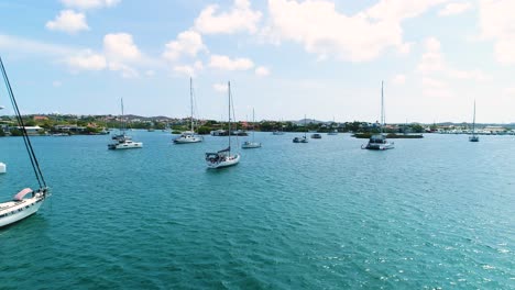 Aerial-dolly-between-catamaran-sailboats-anchored-in-Spanish-Waters,-Curacao