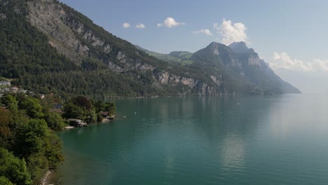 Drone-flying-over-Weesen-town-based-near-shore-of-Walensee-lake,-Switzerland-with-blue-sky