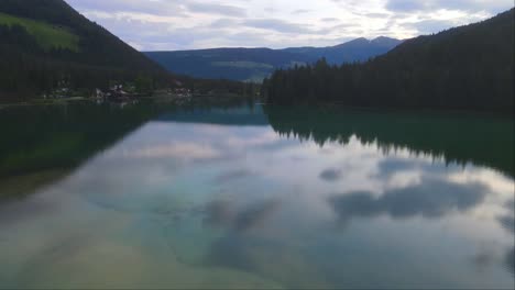 Drone-forward-shot-of-big-Lake-Dobbiaco-and-its-reflection-in-Toblacher-See,-South-Tyrol,-Italy