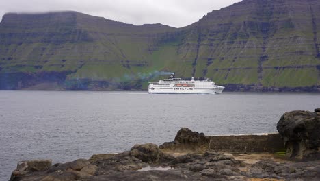 Cruise-ship-sailing-through-Faroe-Islands-fjord-in-front-off-Kunoy-Island