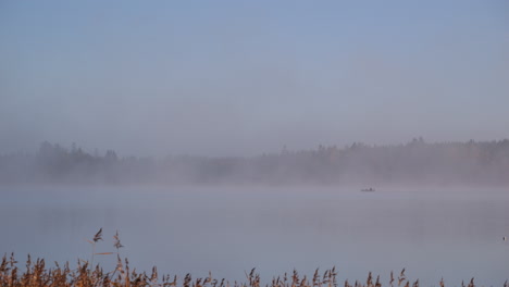 Lone-boat-sailing-near-archipelago-on-foggy-and-peaceful-morning
