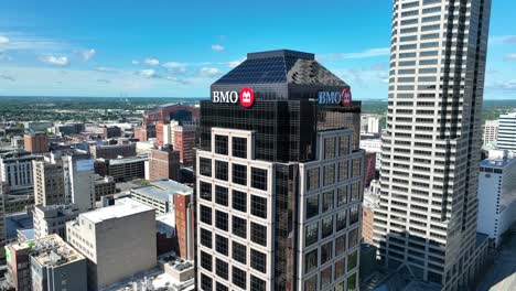 Aerial-view-of-Indianapolis,-showcasing-the-BMO-tower,-other-high-rise-buildings,-and-a-sprawling-urban-landscape-under-a-clear-sky