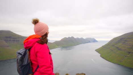 Traveler-woman-looking-fascinated-at-stunning-Kalsoy-and-Kunoy-landscape-from-Bordoy,-Faroe-Islands